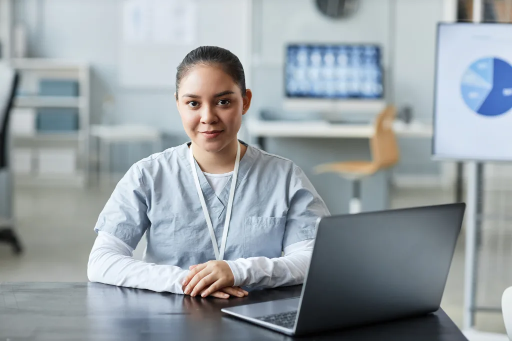 Young pretty female doctor or assistant looking at camera by workplace